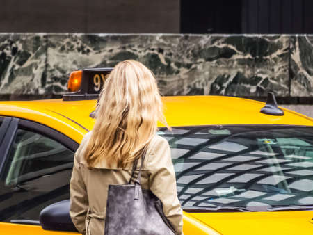 A blonde lady in New York City waits for a taxi.の写真素材