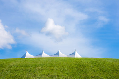 One of the white tents of Bethal Woods and the green hillside of the Woodstock concert grounds.の写真素材