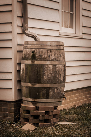A sepia toned image of rain collecting barrel in the backyard.