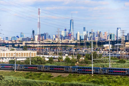Power lines and a commuter train in New Jersey with the New York City downtown skyline in the background.のeditorial素材