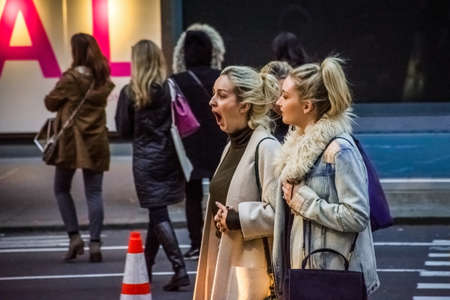 NEW YORK-JANUARY 19 2017: A woman with a big yawn as she crosses the street with a friend on January 19 2017 in midtown Manhattan.のeditorial素材