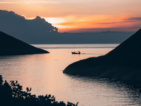 Beautiful sunset over the sea with boat and mountain silhouettes.の写真素材