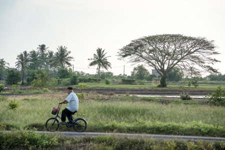 Kedah,Malaysia - 11-05-2019 : the old asian man cycling thru the village in the evening at Kedah,Malaysia.のeditorial素材