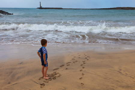 Child on a beach looking at waves