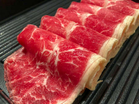 Closeup to fresh sliced Angus chuck roll, thinly sliced to boiled (Shabu, sukiyaki) in hot pot or grilled on charcoal flame (barbecue)の写真素材