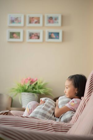 Asian child (Chinese girl) at home during lockdown. watching TVの写真素材