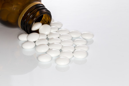 dragee pills and brown bottle white backgroundの写真素材