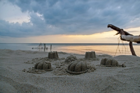 Children's figures of gray sand domed with curlicues and bumps on the background of the sea and the...