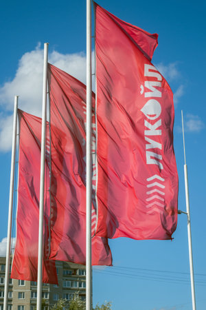 Three white flagpoles with red flags and white inscriptions in Russian LUKOIL, installed at...