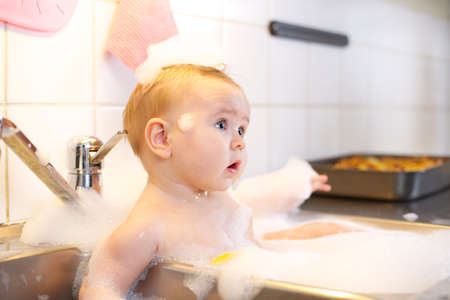 Six month old is bathing in the sinkの写真素材
