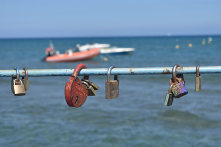 Locks locked to a metal bar and seascape with boats Larnaca