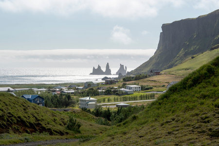 Cloudy landscape of grassy cliffs and buildings in Vik Iceland
