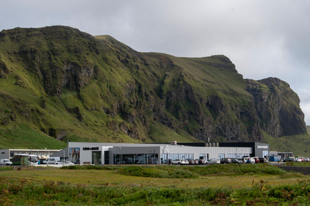 Cloudy landscape of grassy cliffs and buildings in Vik Icelandのeditorial素材