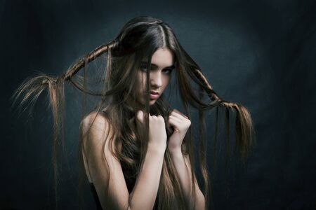 portrait of a beautiful woman with perfect hair on a dark backgroundの写真素材