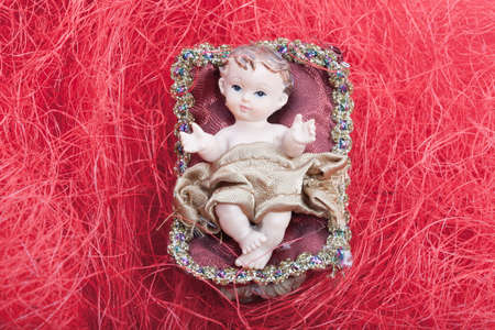 Cradle with Baby Jesus in a Bethlehem Home at Christmas on red backgroundの写真素材