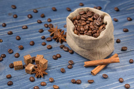 Coffee cereal piled on sackcloth, spices, cinnamon and tubby, boards of blue colorの写真素材