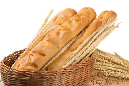 Bread in a wicker basket, French baguette, composition with wheat spikes, grains scattered on a...