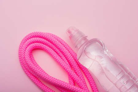 a bottle of water and a pink gymnastic skipping rope on a pink background, minimalism, concept sport and water, copy spaceの写真素材