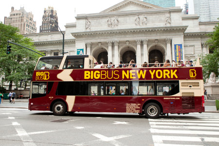 Tourist riding a double-decker tour bus in front of the New York City Library