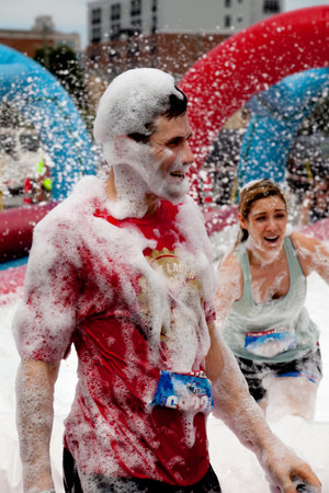 Two Women covered with foam at the Foam of Fury obstacle at the Wipeout 5K Run obstacles course in Wilmington Delaware  The Wipeout Run is themed after the popular ABC game show "Wipeout" and has12 obstacles. Some of the obstacles incorporated in the courのeditorial素材