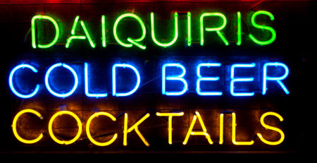 Neon Bar Sign with the words Daiquiris, Cold Beer and Cocktails in colorful neon lights on a black...