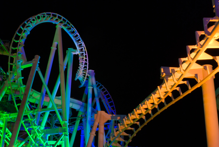 Modern rollercoaster lit up with different colors of light at night.の写真素材
