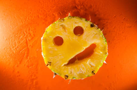 Picture presents One slice of pineapple on orange background, horizontal shotの写真素材