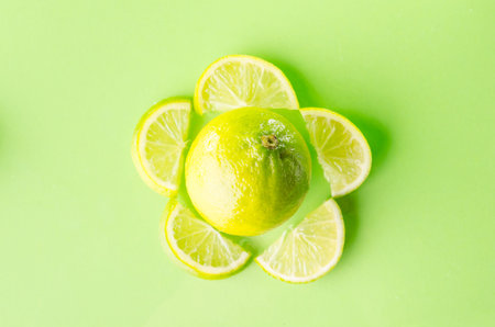 Picture presents slice of lime around one whole on green background, horizontal shotの写真素材