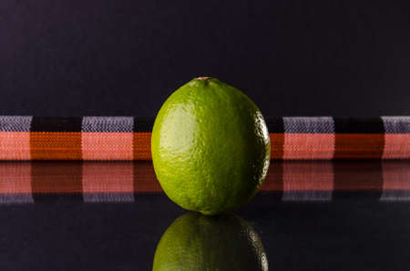 One whole lime on black background with horizontal colour strip, horizontal shotの写真素材
