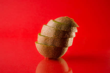 One sliced kiwi fruit isolated on red background, horizontal shotの写真素材