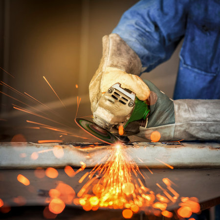 Electric wheel grinding on steel structure by worker in factory
