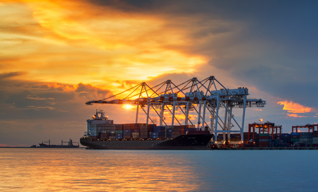 Container Cargo freight ship with working crane bridge in shipyard at dusk for Logistic Import Export backgroundの写真素材