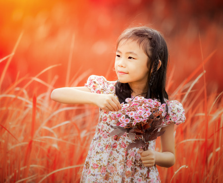 Asia little girl laughing in a meadow - happy girl in autumn backgroundの写真素材