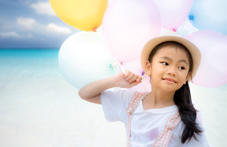 Portrait of asian little girl playing with air balloons at the beach