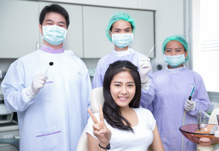 Beautiful asian woman sitting at the dentist while smiling towards the cameraの写真素材