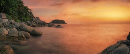 Sunset in phuket beach with rock, island and coconut in Thailandの写真素材
