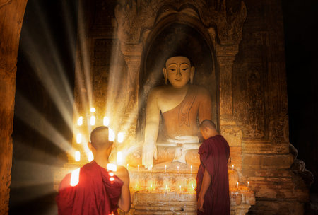 Young Buddhist Monk are reading with sun light from outside to inside pagoda of old bagan with...