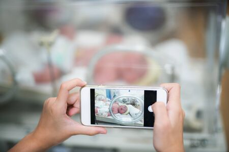 Take a photo for new born baby in hospital by use smart mobile phone, mother and baby conceptの写真素材