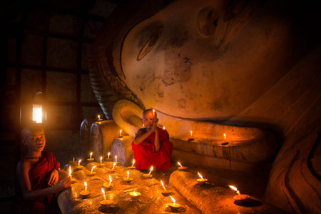 Monk in Bagan old town pray a buddha statue with candle, bagan city, Myanmarのeditorial素材