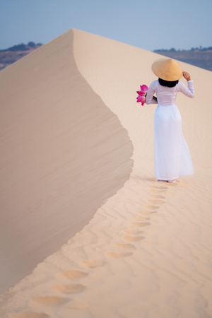 Lady and  lotus flower on hand walk on the sand in Mui ne desert, Vietnamの写真素材