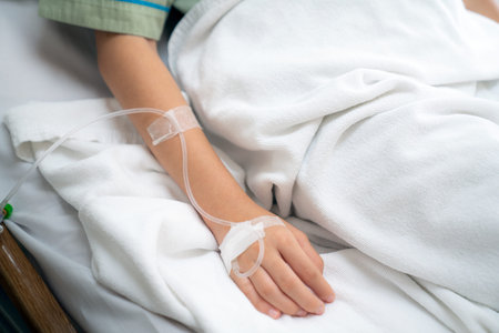 Hospital and patient concept,  Asian patient woman sleep in bed with iv solution on her hand in room...
