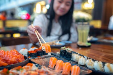 Asian lady eat a Salmon fish sashimi and Sushi in Japanese restaurant for good healthy, Tokyo, Japan. This image can use for  food, and Japanese food conceptの写真素材