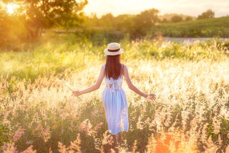 Beauty Asian Girl Outdoors enjoying nature. Beautiful Teenage Model girl in white dress running on the Spring Field, Sun Light.の写真素材