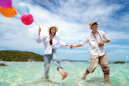 Asian couple run and happy on Pattaya beach with balloon on hand, Thailand, this image can use for travel, love, sweet, summer and valentine conceptの写真素材
