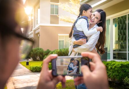 Father mother and daughter take a photo togather by smartphone in front of they home, this image can use for family. house, love and smart phone conceptの写真素材