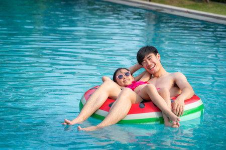 Asian father  play with her daughter in a swimming pool in a tropical resort, this image can use for...