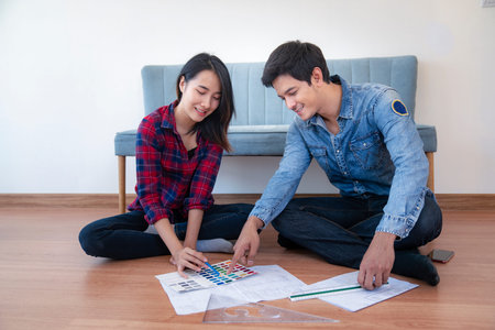 Young happy smiling couple choosing colors for painting their home, this image can use for family,...