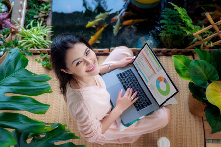 Asian girl use computer notebook and relax in her garden on a hame, this photo can use for work at...