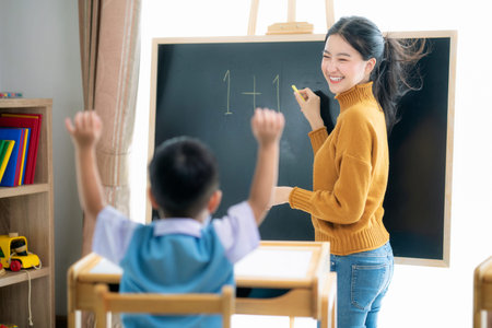 Asian woman teacher and her smart student in class room with backboard background, this image can...