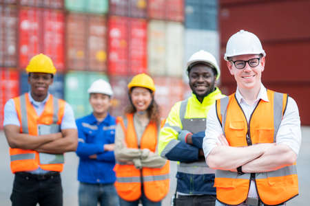 Manager and teamwork standing in container depo company area. Group of worker in logistic and import export hub business standing and smileの写真素材